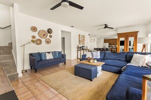 A spacious living area with a sofa set, a coffee table, and a dining area in the background.
