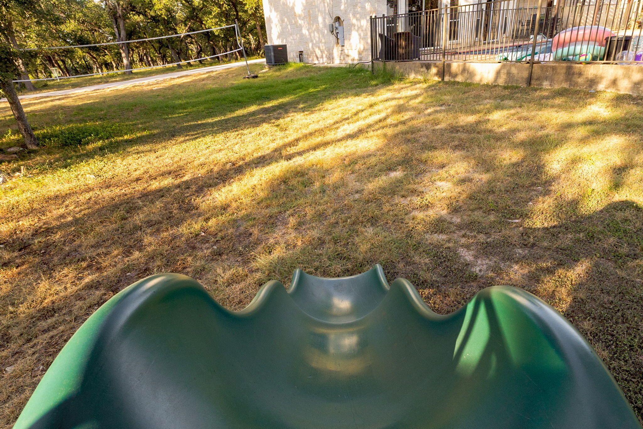 A playground with a green slide and a fenced area.