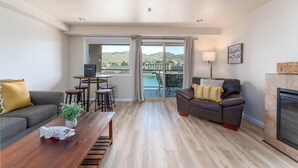 Un salon moderne avec un canapé, une table basse et une cheminée. Il y a un balcon avec vue sur la piscine.