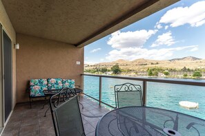 Ein Balkon mit Blick auf einen See, einer Couch und einem Tisch.