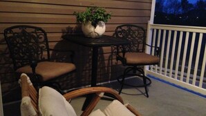 A patio with wicker furniture, a table with a potted plant, and a railing.