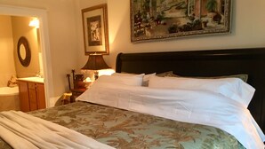 A neatly made bed with a floral bedspread, a bedside lamp, and a framed picture on the wall.