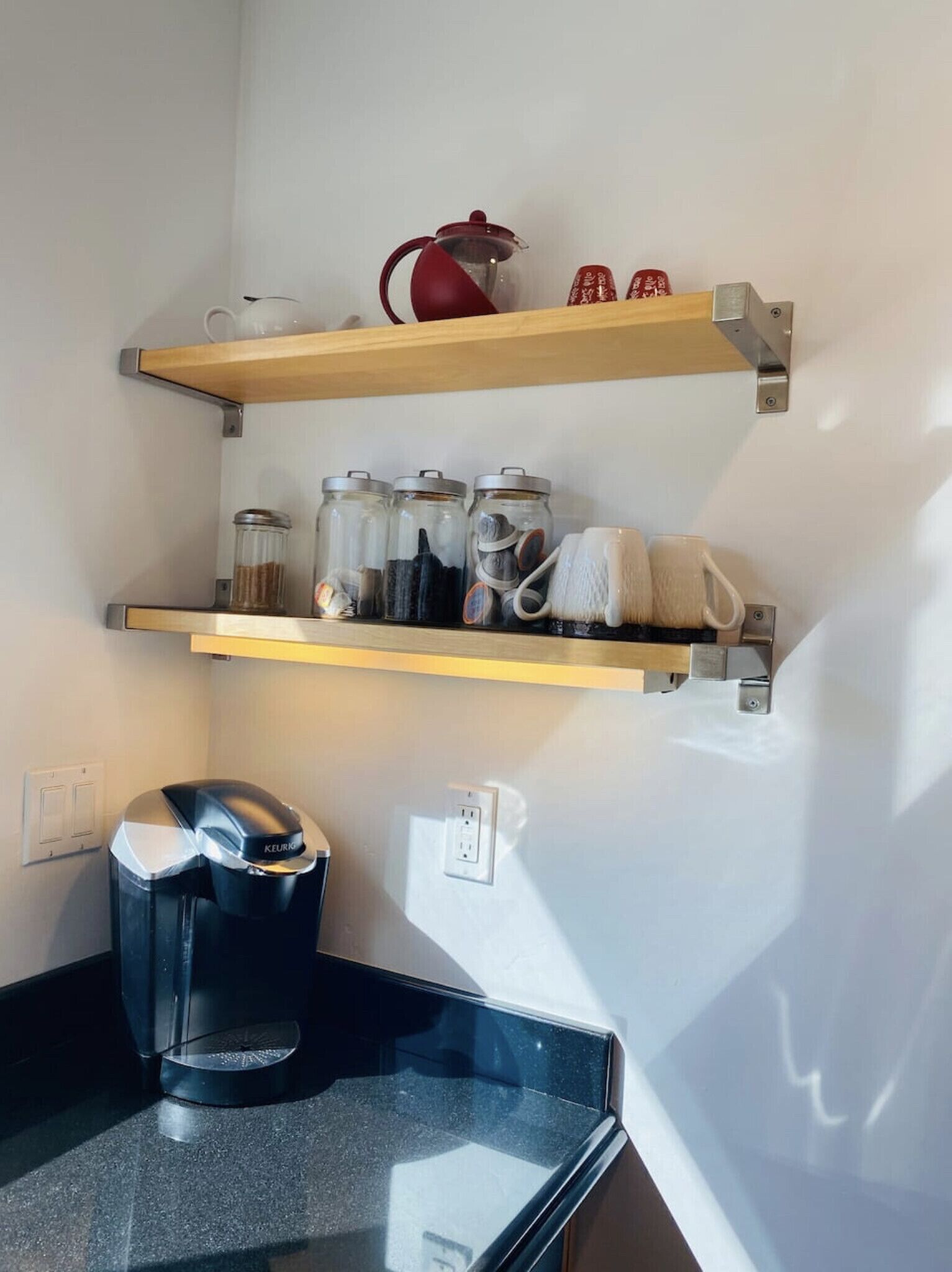 Een kitchenette met twee houten planken, een koffiezetapparaat en diverse keukenbenodigdheden.