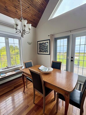 A dining area with a wooden table, chairs, a chandelier, and large windows with a view. - Gorgeous Private Chalet on 10 acres (Belfast)