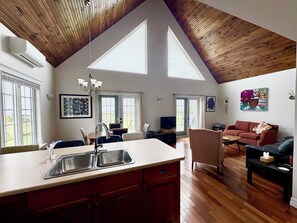 A spacious living area with a kitchen, dining table, and a large window. - Gorgeous Private Chalet on 10 acres (Belfast)
