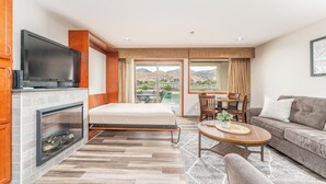 Quarto de hotel moderno com lareira, cama, sofá, mesa de jantar e televisão.