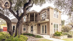 A two-story house with a balcony, a stone facade, and a well-maintained garden. - Huge Home in Downtown ATX/Large Groups Welcome/Walk Everywhere!!! (Austin)