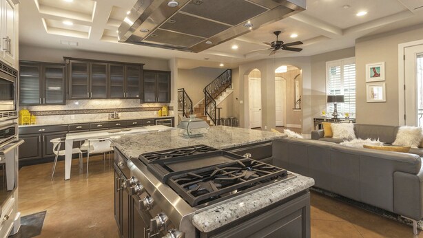 A spacious kitchen with dark cabinets, a large island, a gas stove, and a ceiling fan. - Huge Home in Downtown ATX/Large Groups Welcome/Walk Everywhere!!! (Austin)