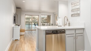 A modern kitchen with a dishwasher, white cabinets, and a view to a dining area. - Grandview 627 Waterfront condo on Lake Chelan (Chelan)