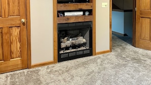 Una habitación con chimenea, puertas de madera y un televisor sobre una estantería.