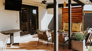 An outdoor patio with a table and chairs, a ceiling fan, and a wooden wall. - The Phx Bungalow located in north-central phoenix. (Phoenix)