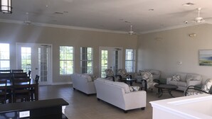Ein geräumiges Wohnzimmer mit Essbereich, großen Fenstern und Deckenventilatoren.