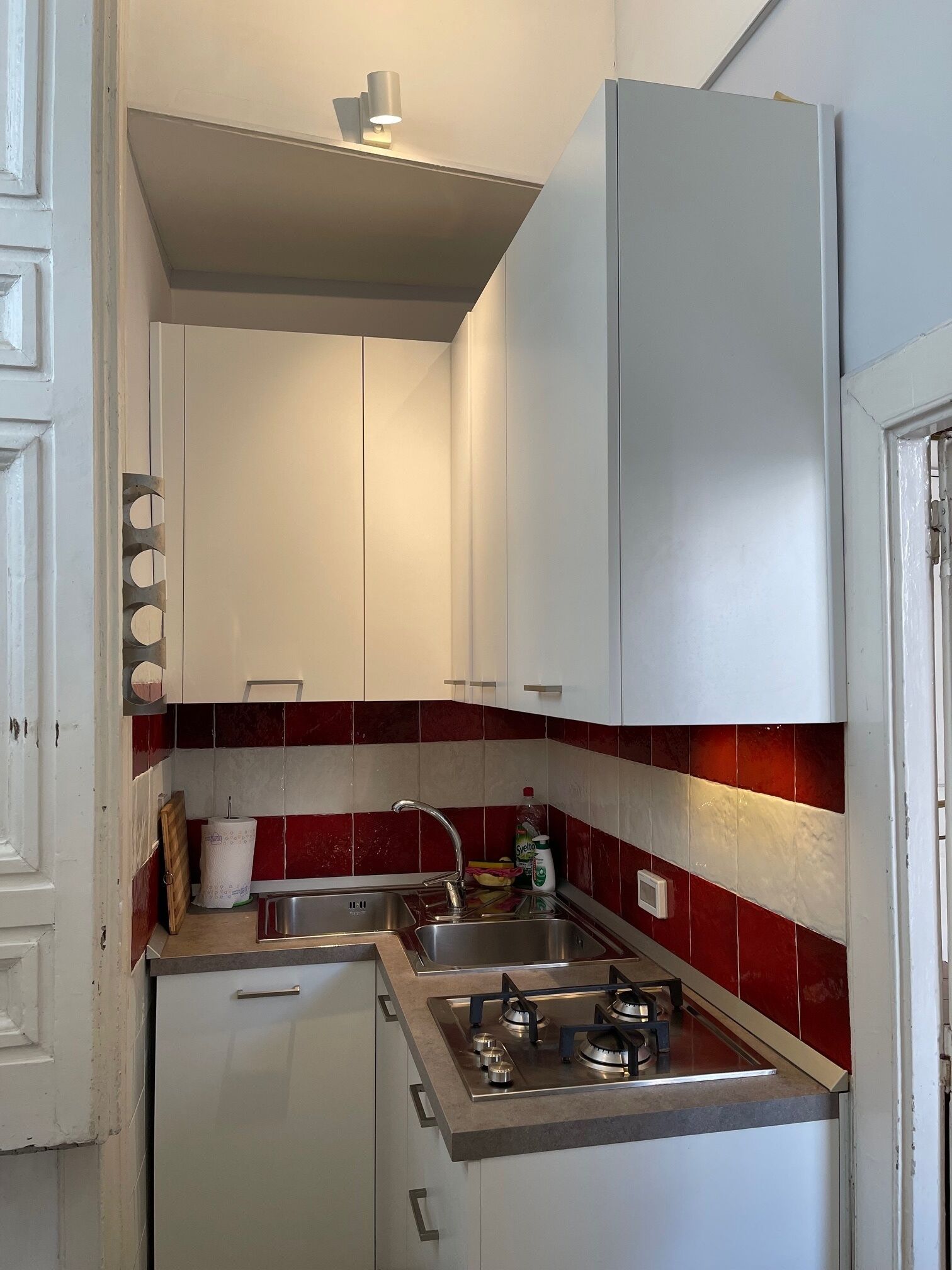 A compact kitchen with white cabinets, a stainless steel sink, and a gas stove.