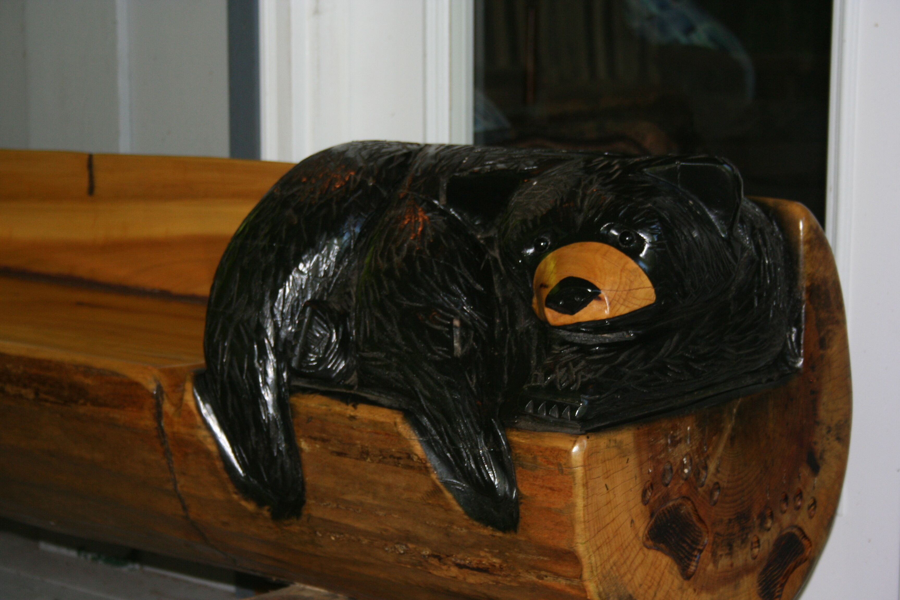 A wooden bench with a carved bear figure resting on it.