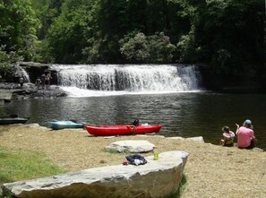 Una cascada, kayaks y gente cerca del agua.