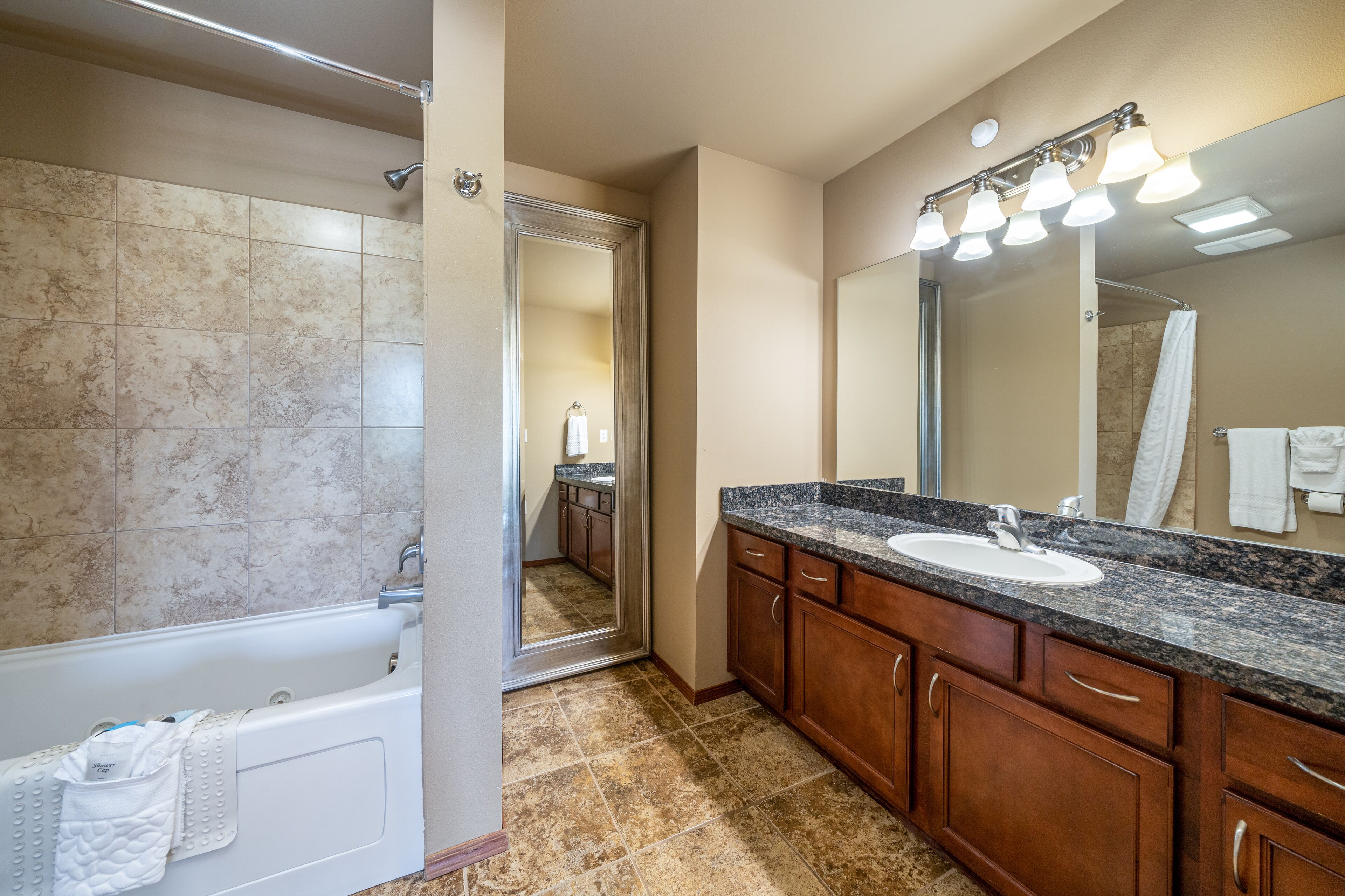 A bathroom with a bathtub, a sink, and a large mirror.