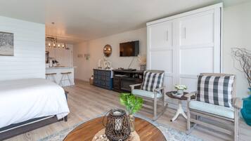 A modern hotel room with a bed, a desk, a chair, and a coffee table.