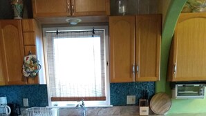 Una cocina con armarios de madera, salpicadero de azulejos, un lavamanos y suelo estampado.