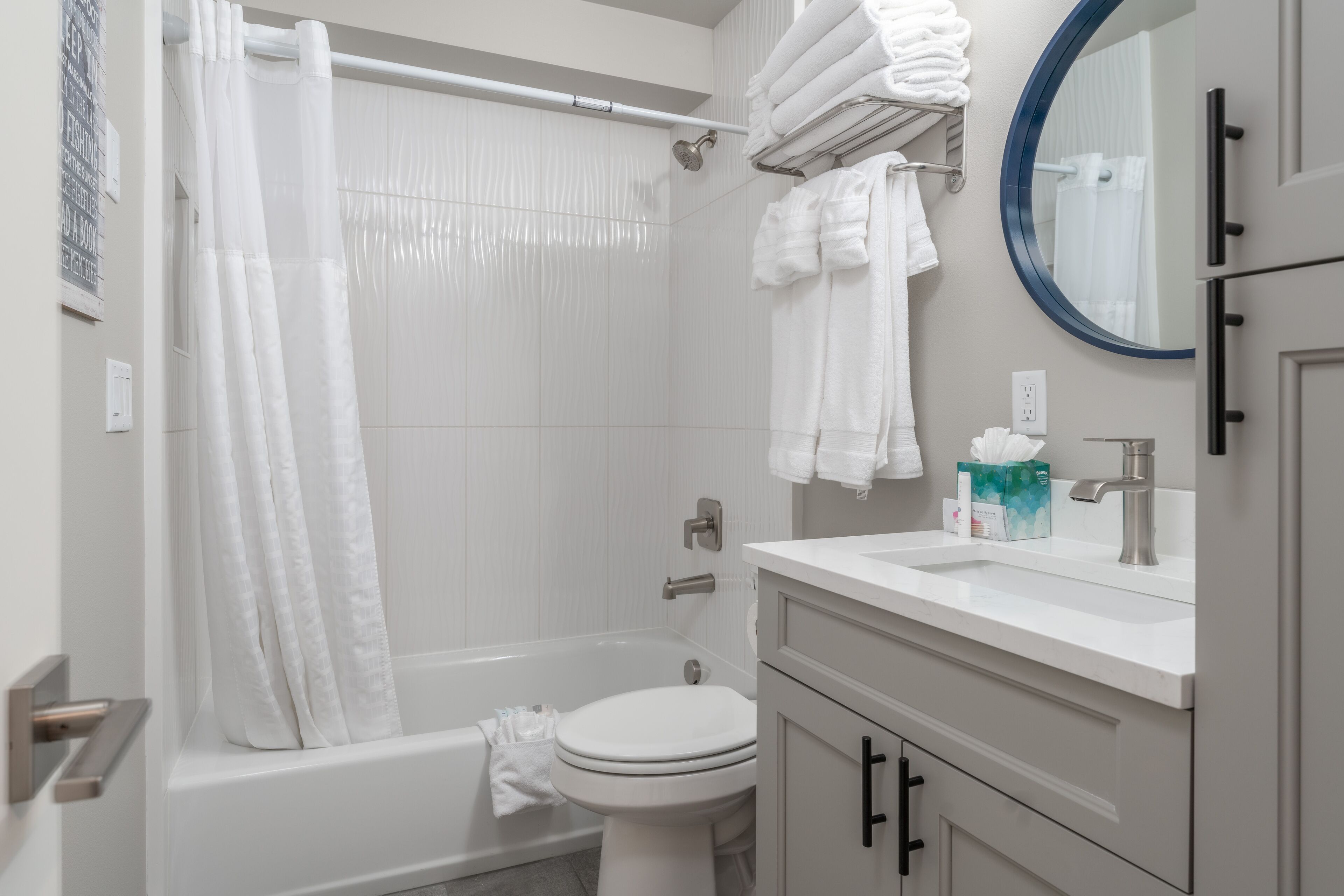 A modern bathroom with a bathtub, toilet, sink, and a mirror.