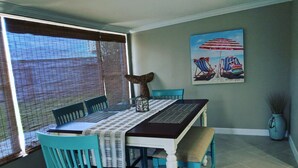 A dining area with a table set for four, surrounded by turquoise chairs. - Super Cute Beach Home *Recommended** Casa Azalea (Ormond Beach)