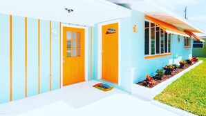 A modern house with a bright exterior, a front porch, and a small garden. - Super Cute Beach Home *Recommended** Casa Azalea (Ormond Beach)
