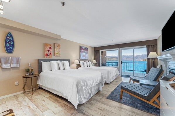 Habitación de hotel con dos camas, balcón con vistas y zona de estar con televisión.