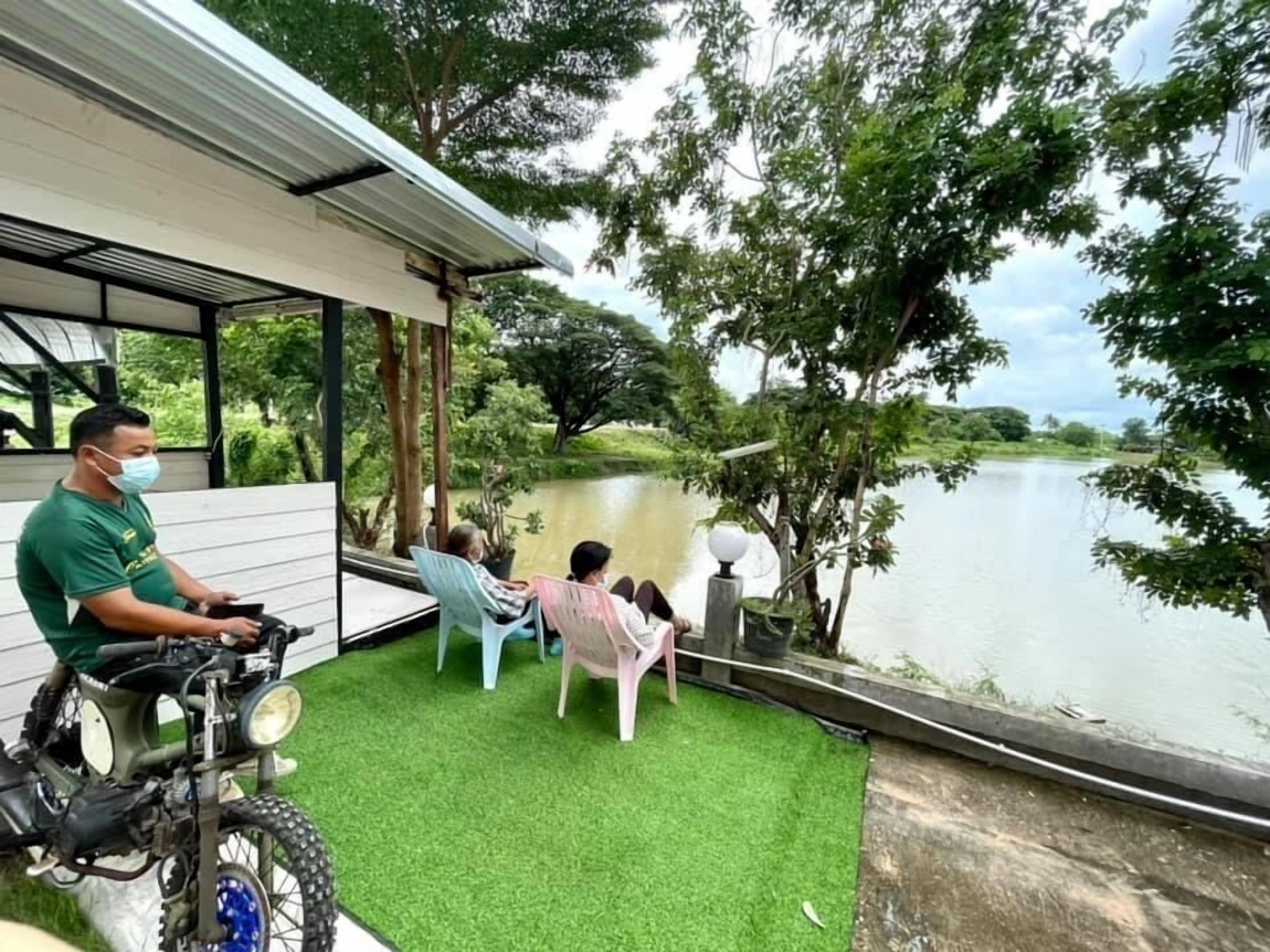 A covered outdoor seating area with a view of a lake, a motorcycle, and a person in a green shirt.