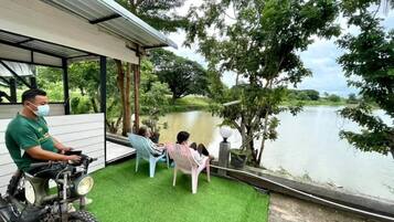 A covered outdoor seating area with a view of a lake, a motorcycle, and a person in a green shirt.