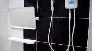 Un espace douche équipé d’un pommeau de douche blanc et d’un panneau de commande.
