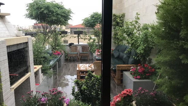 Une cour avec un four en briques, un espace aménagé pour s’asseoir et des plantes en pot.