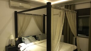 Un lit à baldaquin, une table de chevet avec une lampe et une fenêtre avec des rideaux.