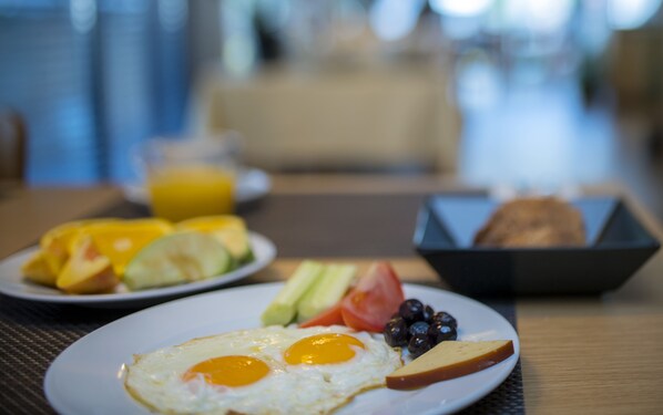 A breakfast plate with eggs, toast, and fruit.