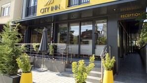 A CITY INN building with a reception area, outdoor seating, and potted plants. - City Inn (Pristina)