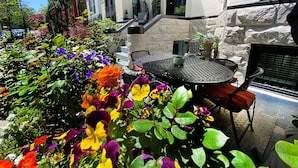 An outdoor patio with a stone wall, a black metal table, and chairs.