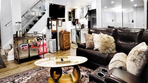 A modern living room with a leather sofa, a coffee table, and a kitchen area in the background.