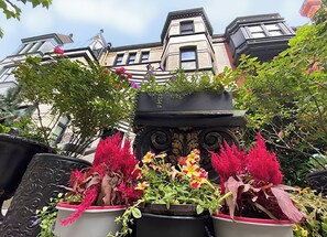 Un bâtiment doté d’une façade décorative, de grandes fenêtres et d’un balcon agrémenté de plantes en pot.