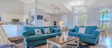 A spacious living room with teal sofas, a wooden coffee table, and a starfish-patterned rug.