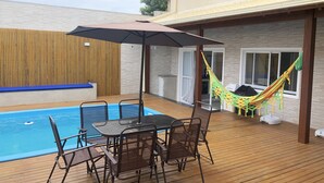 Ein Poolbereich mit Tisch, Stühlen und einer Hängematte.