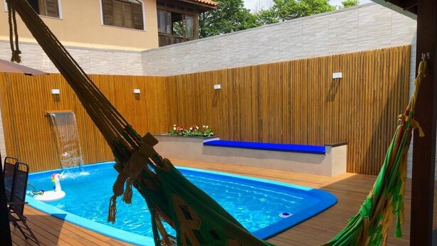 Eine Holzterrasse mit Swimmingpool, einer Hängematte und einer Sitzbank.