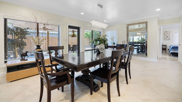 A spacious dining area with a large wooden table, six chairs, and a chandelier. - PRIVATE ISLAND HOME WITH POOL & WALK TO PRIVATE BEACH - GUEST FAVORITE! Must see (Pompano Beach)