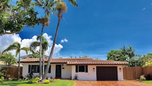 A single-story house with a tiled roof, a garage, and a well-maintained lawn with palm trees. - PRIVATE ISLAND HOME WITH POOL & WALK TO PRIVATE BEACH - GUEST FAVORITE! Must see (Pompano Beach)