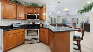 A kitchen with wooden cabinets, stainless steel appliances, a central island, pendant lighting, and a view to the dining area. - PRIVATE ISLAND HOME WITH POOL & WALK TO PRIVATE BEACH - GUEST FAVORITE! Must see (Pompano Beach)