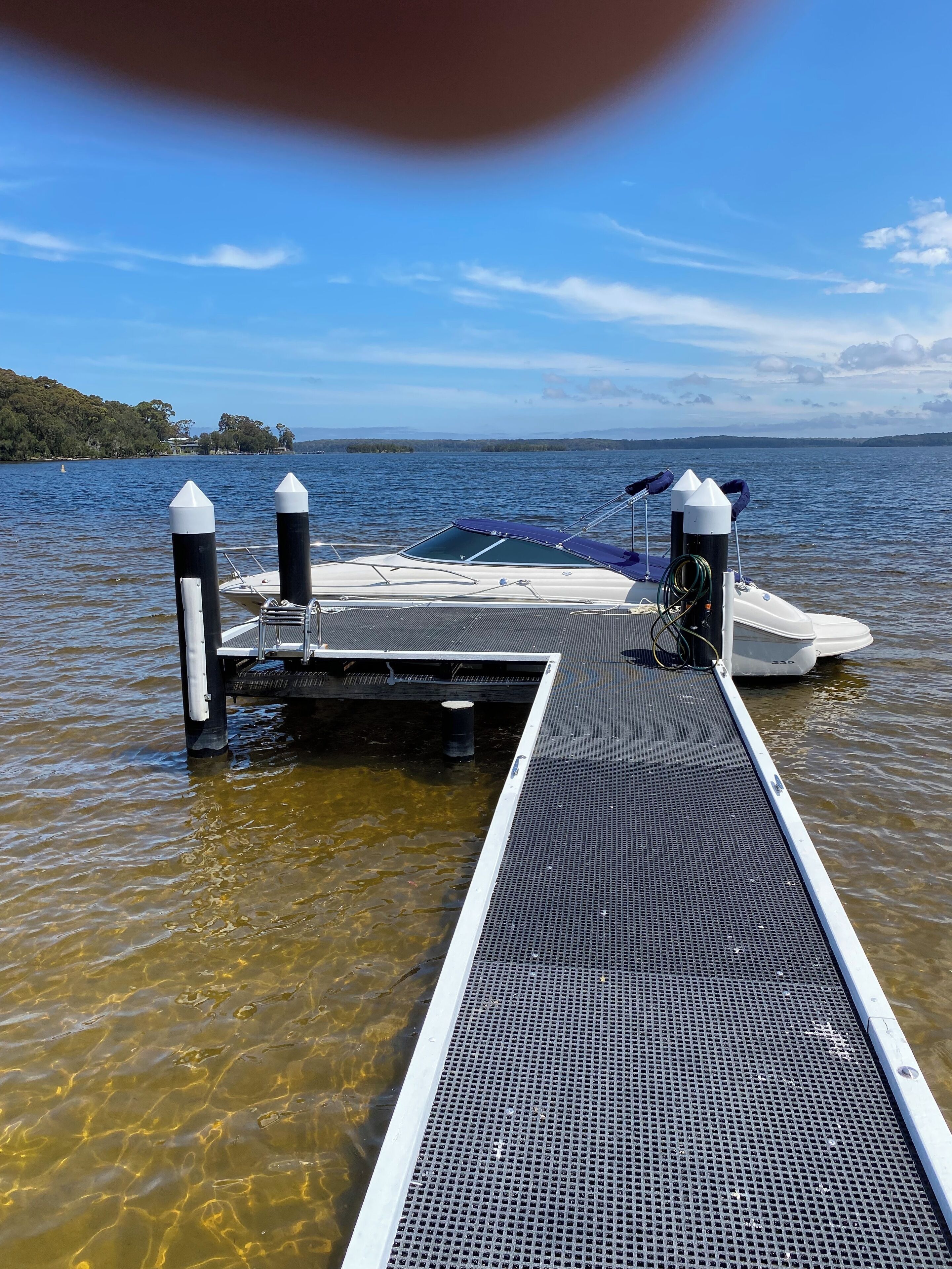 Ein klares Gewässer, das zu einem Steg mit einem dort festgemachtem Boot führt.