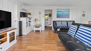 Una sala de estar moderna con un sofá de cuero negro, un televisor de pantalla plana y un mueble de madera.