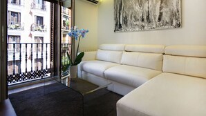 Ein modernes Wohnzimmer mit einem weißen Sofa, einem Glastisch und einer Topfpflanze.