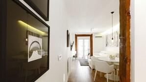 Ein modernes Interieur mit Holzboden, weißen Wänden und einem Essbereich mit weißen Stühlen und einem runden Tisch.