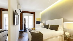 Ein modernes Hotelzimmer mit einem großen Bett, Nachttischen, einem Fernseher und Blick ins Freie.