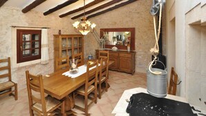 Una sala da pranzo rustica con arredi in legno, un lampadario e travi a vista.