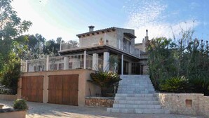 Una casa a due piani con un balcone, scale in pietra e un vialetto lastricato.