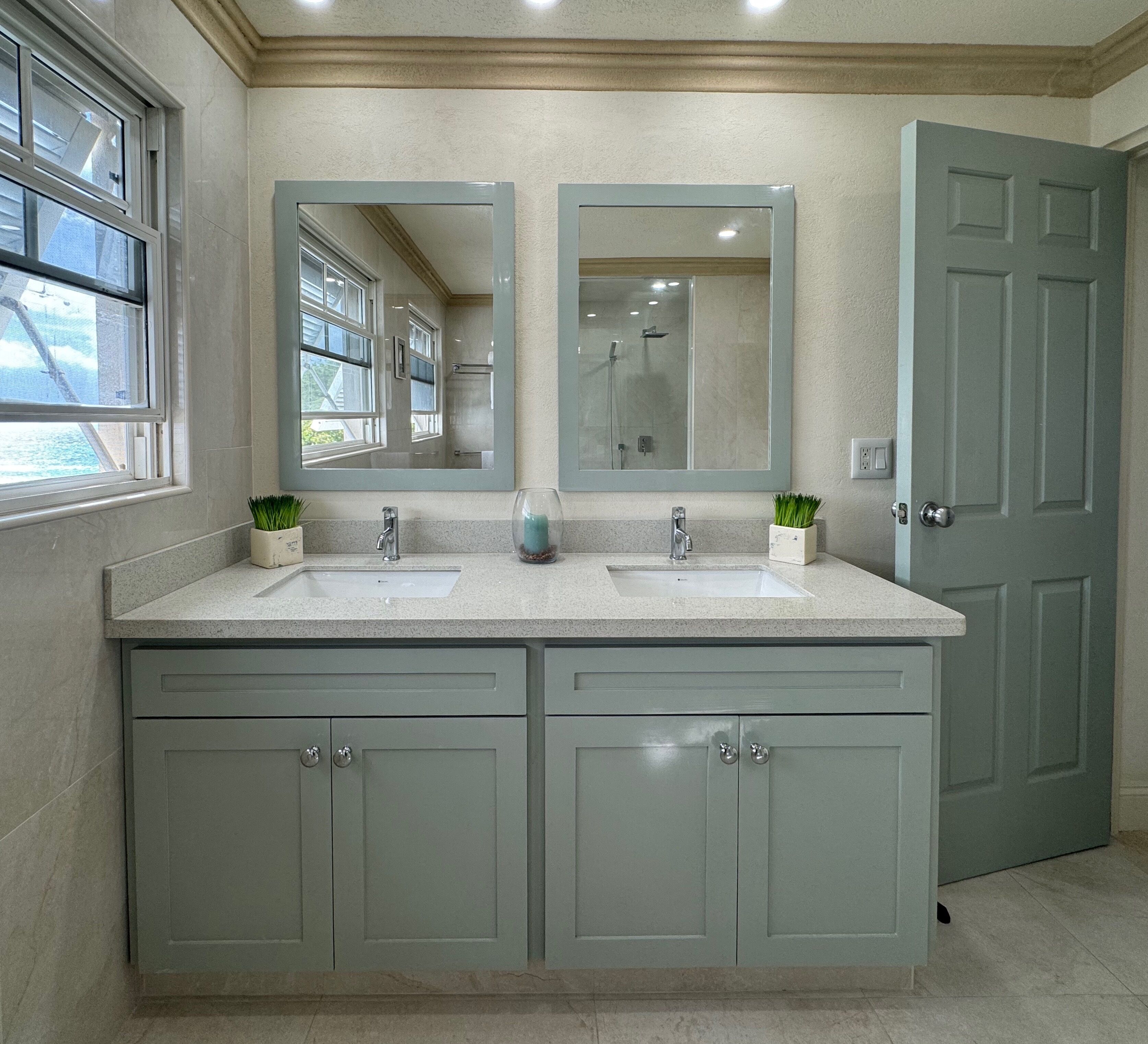 A bathroom with two sinks, a large mirror, and a door.